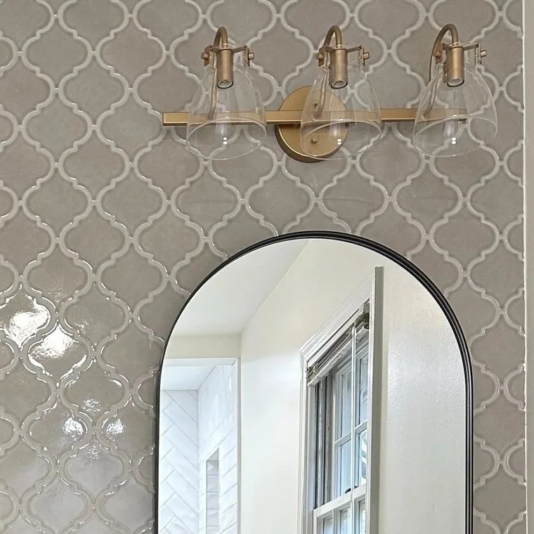 Arabesque wall tile with a brass sconce mounted on it
