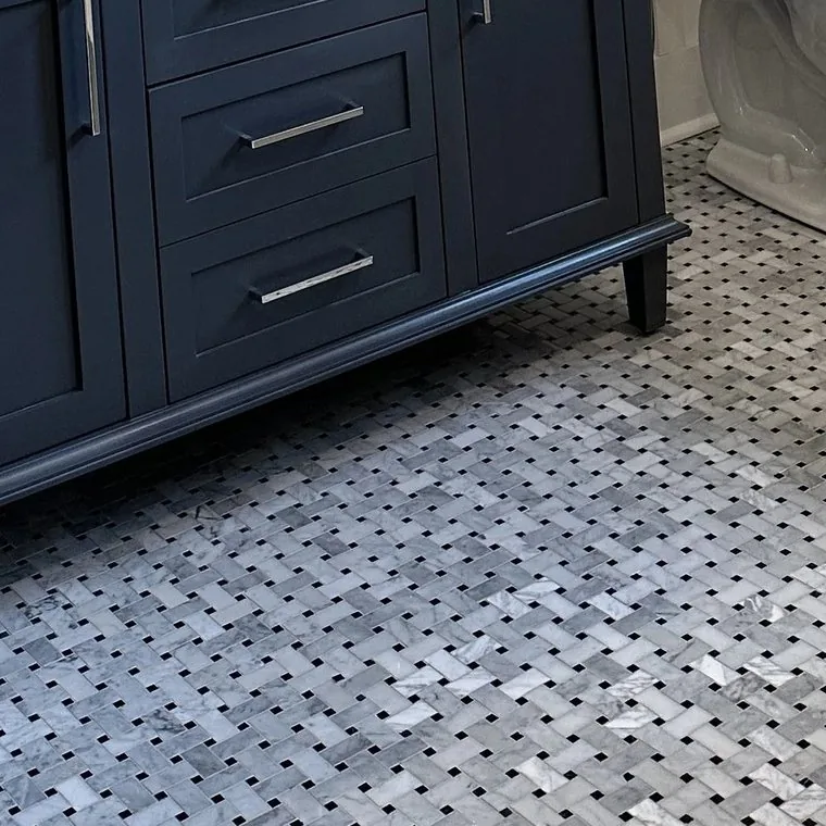 Basketweave marble mosaic floor cut around the legs of a navy vanity