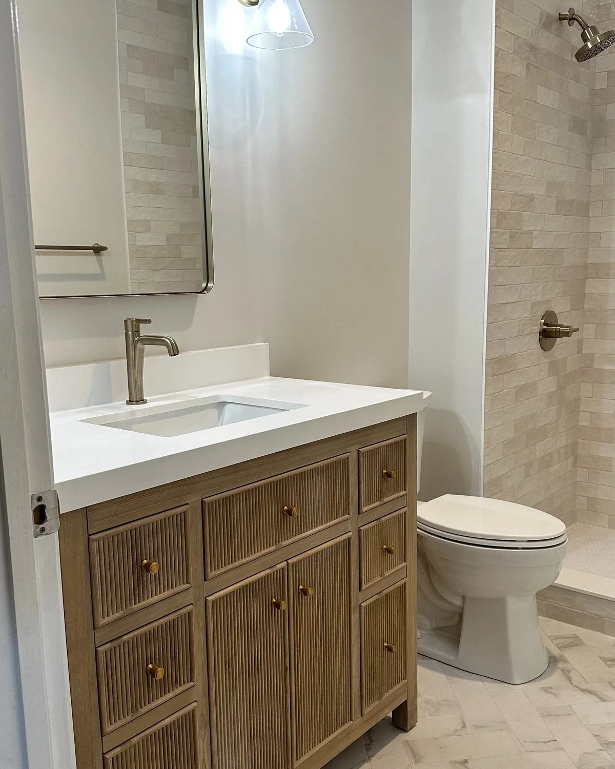 A bathroom with a fluted wood vanity and a tiled walk-in shower