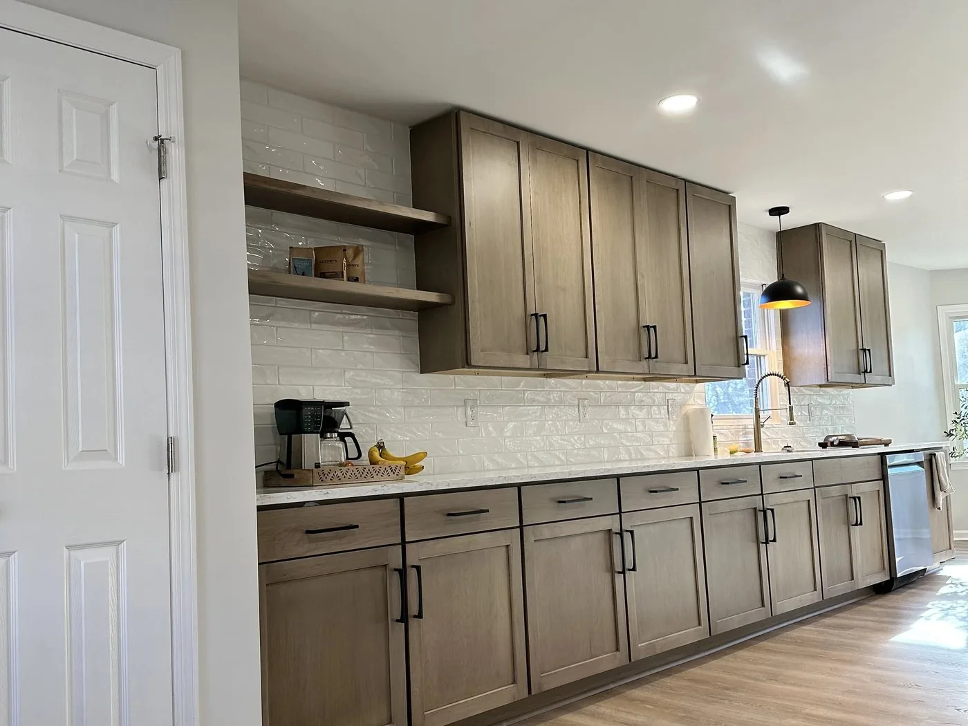 A kitchen with stained wood cabinets, open shelving and a white subway backsplash